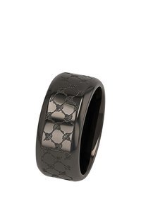 Anello in ceramica nera con una larga fascia, caratterizzato da un motivo a rilievo di fiocchi e anelli, finitura liscia e bordi arrotondati.