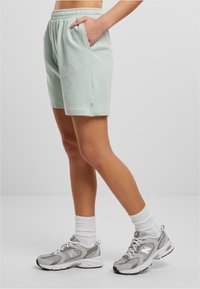 Mint green cotton shorts with an elastic waistband and side pockets, paired with grey and white sneakers and white ankle socks.