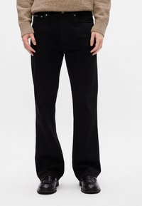 Juodos džinsinio audinio kelnės su aukštu liemeniu, tiesiomis kojomis, penkiomis kišenėmis ir metaliniais priedais. Tekstūra yra lygi su švelniu blizgesiu.