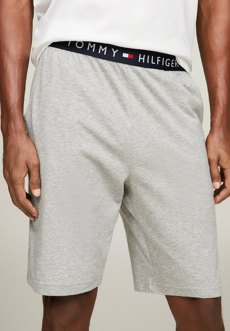 Grijze katoenen shorts met een elastische tailleband en een marineblauwe logoband. De textuur is glad en de shorts hebben een losse pasvorm.