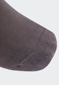 Calcetín de lana morado con una textura suave, punta redondeada y talón reforzado. Detallado con costuras finas y un patrón consistente.