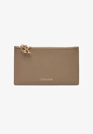 Porte-cartes en cuir beige Calvin Klein avec curseur de fermeture éclair doré portant le logo "cK" et détails cousus.