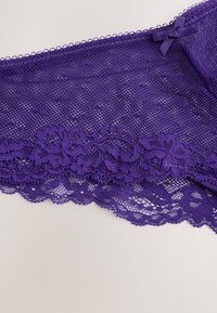Lila spetsunderkläder med ett blommönster nederst, med ett nätmönster och picotkant längs kanterna.