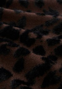 Brązowa tkanina o miękkiej fakturze z czarnym wzorem w panterkę, prezentująca wyraźne plamy przypominające futro oraz gładkie fale.