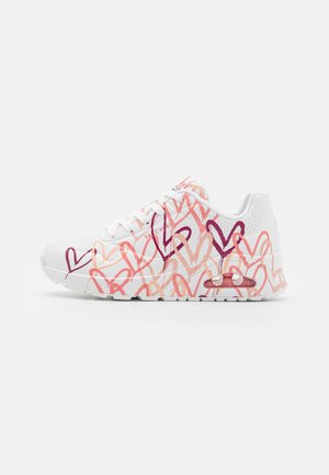 White sneakers featuring a textured upper with multicolored heart patterns in shades of pink and purple, and a visible air cushioning unit.