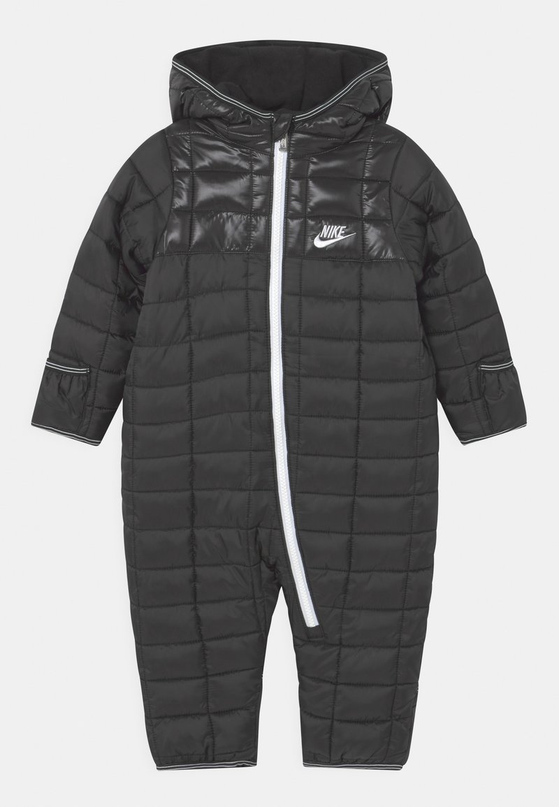 Combinaison de neige pour bébé Nike en tissu matelassé noir avec capuche, fermeture éclair diagonale blanche sur le devant et logo sur la poitrine.