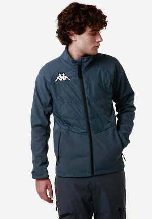 Giacca grigia scura con colletto alto, chiusura con zip e logo Kappa sulla spalla sinistra. Presenta pannelli testurizzati e tasche con zip.