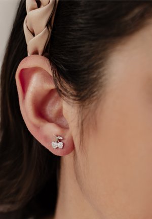 Silver cherry-shaped earrings with a shiny finish. One cherry is embellished with clear crystals; the design features a small green leaf accent.