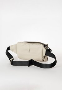 Borsa rettangolare beige realizzata in tessuto resistente con una tracolla nera regolabile e chiusura con zip. Presenta una tasca frontale e una superficie liscia.