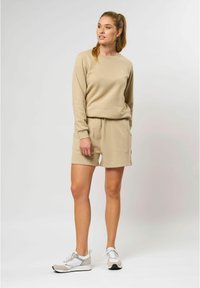 Beige sweatshirt met een ronde hals en een subtiel logo, gecombineerd met bijpassende shorts met een elastische tailleband en zijzakken.