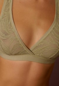 Krajkový bralet v olivovej zelenej farbe s mäkkým elastickým pásom, hlbokým výstrihom do V a zložitým listovým vzorom na priesvitnej sieťovine.