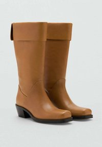 Bottes en cuir marron, hautes, avec un revers plié, bout rond, couture discrète et un petit talon carré. Texture lisse et design épuré.