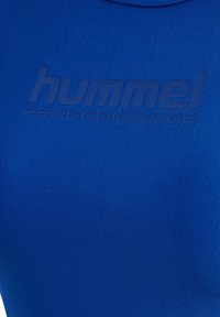 Niebieska, elastyczna koszulka sportowa o gładkiej fakturze z wytłoczonym logo "hummel PERFORMANCE" w ciemniejszym odcieniu niebieskiego.
