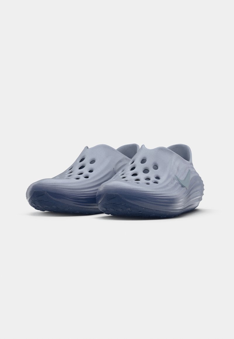 Par de zapatos gris slip-on con empeine perforado y logo de Nike, fabricados con material ligero y moldeado, con suelas texturizadas.