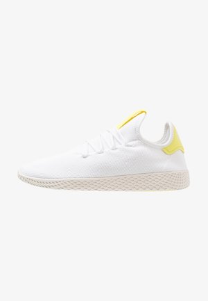 Baskets en mesh blanc avec semelle beige texturée, lacets blancs et accents jaunes au talon et à la languette sur fond blanc.