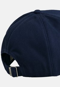 Navy blue baseball cap with a structured design, curved brim, and adjustable strap featuring metal hardware. Smooth texture with visible stitching.