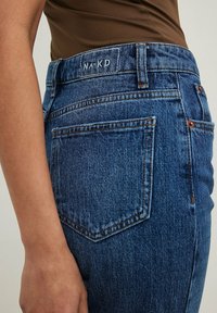 Jeans de mezclilla azul de cintura alta con etiqueta NAKD, que presentan costuras en contraste, bolsillo trasero y un diseño ajustado.