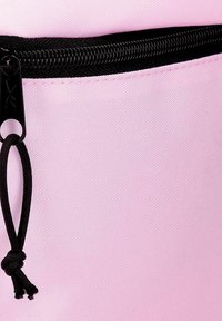 Primer plano de una bolsa de tela de color rosa claro con una cremallera negra y una lengüeta de tirador de cordón negro.