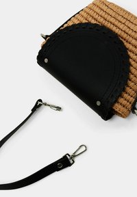 Tkaná béžová kabelka s černou umělou koženou klopou a detailním pletením na okrajích. Obsahuje odnímatelný černý popruh s kovovými prvky.