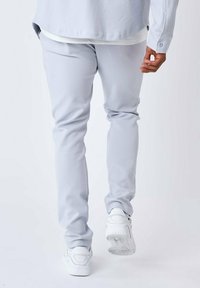 Lys grå joggbukser i blød stof, med en tætsiddende benform og elastisk talje, parret med hvide sneakers.