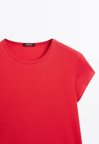 Red short-sleeve crew neck t-shirt with a visible black brand label at the neckline on a white background.