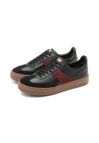 Sneakers in pelle nera con striscia laterale in suede bordeaux, suola in gomma marrone testurizzata e lacci neri. Dettaglio di branding oro sulla linguetta.