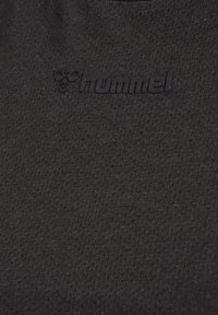 T-shirt de sport noir en tissu texturé, avec un logo en relief discret "hummel" sur le devant à des fins de marque.