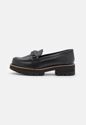 Mocassin en cuir noir avec semelle épaisse crantée, bordure marron et détail chaîne décorative sur le dessus, vu de profil latéral.