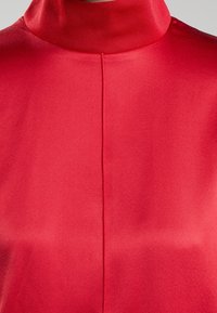 Rotes Satin-Gewand mit hohem Kragen und glatter Textur, das eine zentrale Naht auf der Rückseite aufweist.
