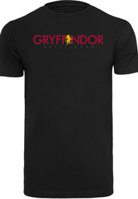 Melna kokvilnas T-kreklu ar uzrakstu "GRYFFINDOR" sarkanā krāsā un zelta lauvu grafiku, apaļu kakla izgriezumu un īsām piedurknēm. Vienkārša dizaina un viendabīgas auduma faktūras.