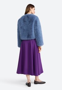 Faux fur jacket in light blue, paired with a purple skirt. The outfit features textured materials and a relaxed fit. Brown flat shoes complete the look.