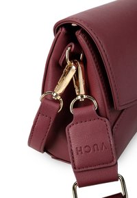 Bordeaux farbene Lederhandtasche mit glatter Oberfläche, ausgestattet mit goldenen Beschlägen und einem abnehmbaren Riemen. Mit Logo-Detail akzentuiert.