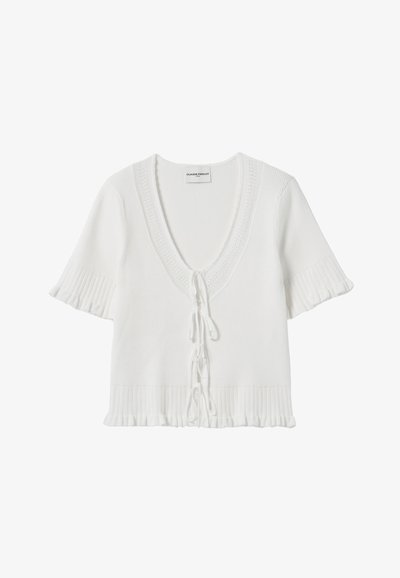 Haut tricoté blanc avec des manches courtes à volants, un décolleté en V profond et une taille cintrée avec des liens décoratifs. Motif en côtes texturé.