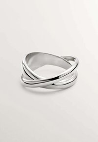 Brazalete retorcido de plata que presenta superficies metálicas suaves y pulidas, con un diseño de bucle continuo, reflejando la luz con un acabado brillante.