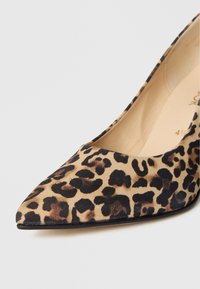 Høye hæler med leopardmønster laget av mykt materiale, med spiss tå og en glatt tekstur med svarte detaljer langs kanten.