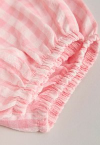 Tissu vichy rose et blanc avec ourlet froncé élastiqué sur un vêtement.