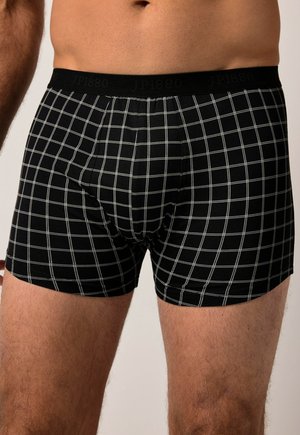 Shorts de boxe noirs arborant un motif à carreaux blancs, une taille élastique avec logo et un design ajusté pour le confort.