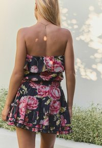 Bezramenné květinové šaty z tmavě námořnické látky s velkými růžovými růžemi, volánkovým vrškem, elastickým pasem a vrstveným střihem sukně.