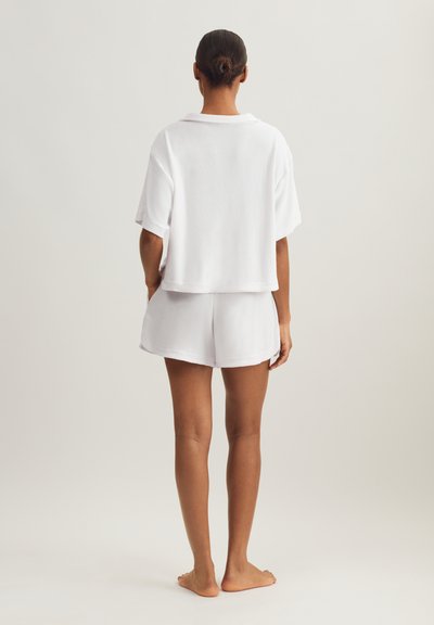 Σετ από λευκό βαμβακερό περκάλι με κοντό μανίκι και σορτς. Το τοπ έχει γιακά, ενώ το σορτς διαθέτει ελαστική μέση. Ομαλή υφή.