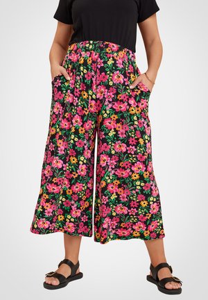 Bloemmotief brede broek in zwart met levendige roze, oranje en gele bloemen. Voorzien van een elastische tailleband en zijzakken.