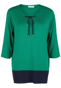 Tunic verde con orlo blu navy, maniche a tre quarti, scollatura a V e un accento con cordoncino al collo. Texture del tessuto liscia.