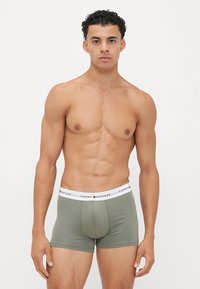 Olijfgroene katoenen boxershorts met een strak ontwerp, voorzien van een witte elastische tailleband met het merk "TOMMY HILFIGER." Glad aanvoelende stof.
