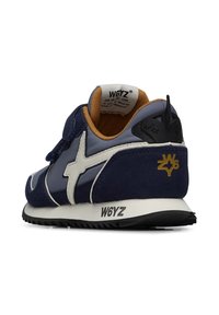 Sneaker blu navy con accenti bianchi, tomaia in suede e mesh, dettaglio del tallone nero e suola con motivo. Presenta una chiusura in velcro e un logo.
