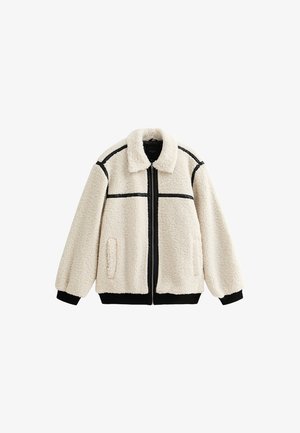 Veste en polaire couleur crème avec des accents noirs, col montant, fermeture zippée sur le devant et poches latérales. Présente un matériau texturé et doux.