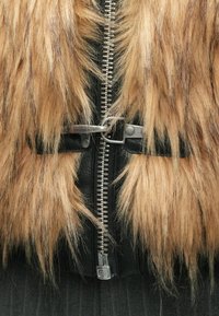 Casaco de pêlo sintético com pelo castanho e preto, fecho de correr prateado e detalhes em pele. O design inclui um fecho com fivela e um acabamento texturizado.