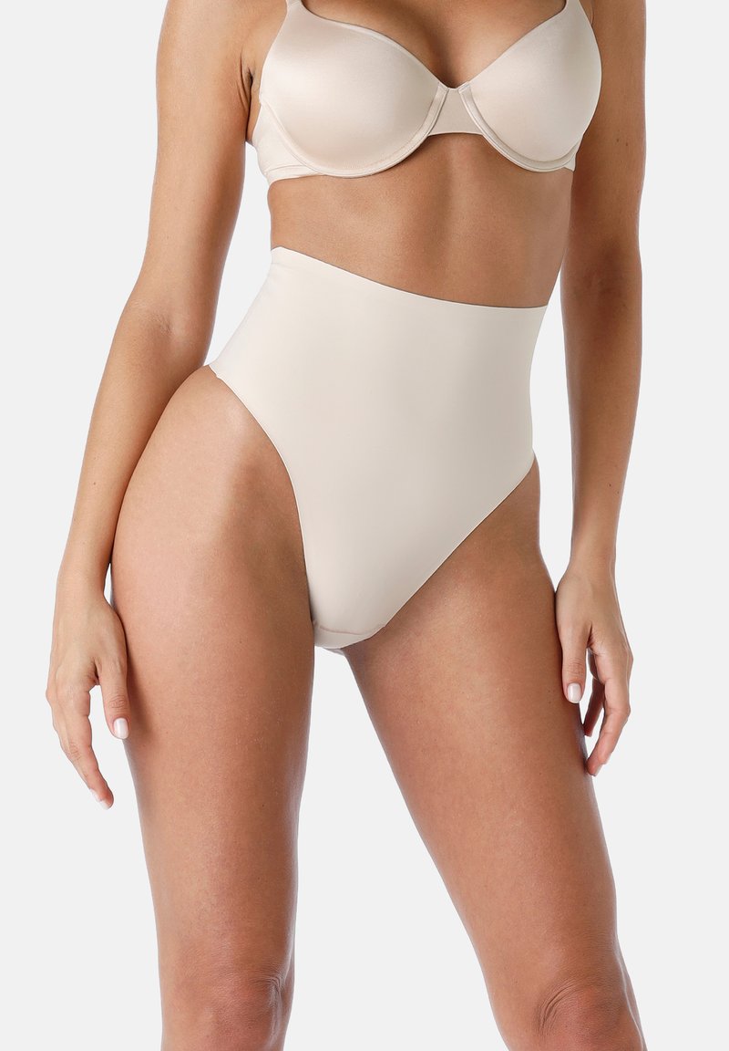 Shapewear alta vita di un beige chiaro con texture liscia e bordi curvi, progettata per un fit senza soluzione di continuità sul corpo.