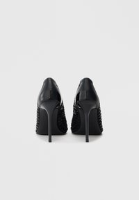 Scarpe con tacco alto nere con finitura lucida in vernice e dettagli in tessuto intrecciato. Design a punta; tacchi a spillo sottili.