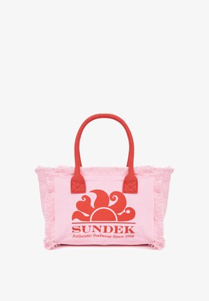 Sac cabas rose avec anses rouges et bords frangés, arborant un logo soleil rouge et le texte « SUNDEK Authentic Surfwear Since 1958 » à l'avant.