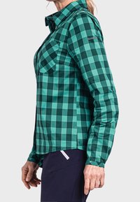Green and teal checkered long-sleeve shirt with a collar, two chest pockets, and adjustable cuffs, made of lightweight fabric.