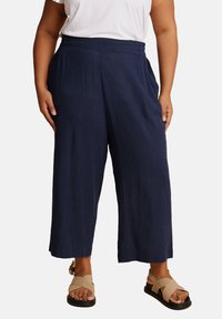 Granatowe spodnie z szerokimi nogawkami wykonane z lekkiego materiału o teksturowanej powierzchni. Posiadają elastyczny pas i luźny krój.